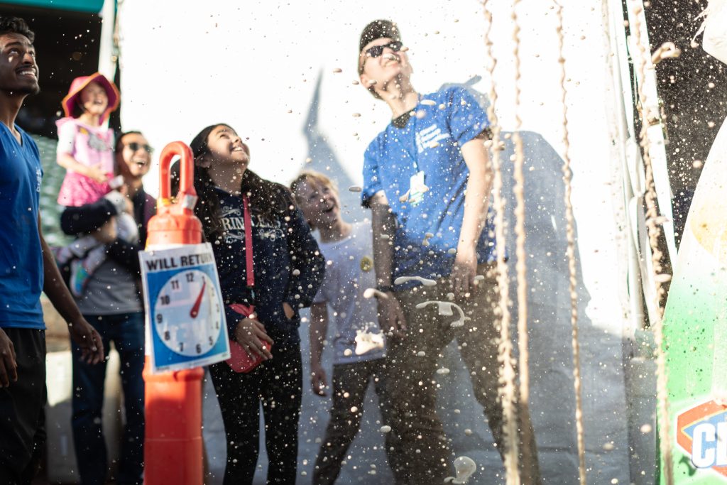 Excited attendees watch soda explode out of 2 liter bottles in a mentos and soda experiment