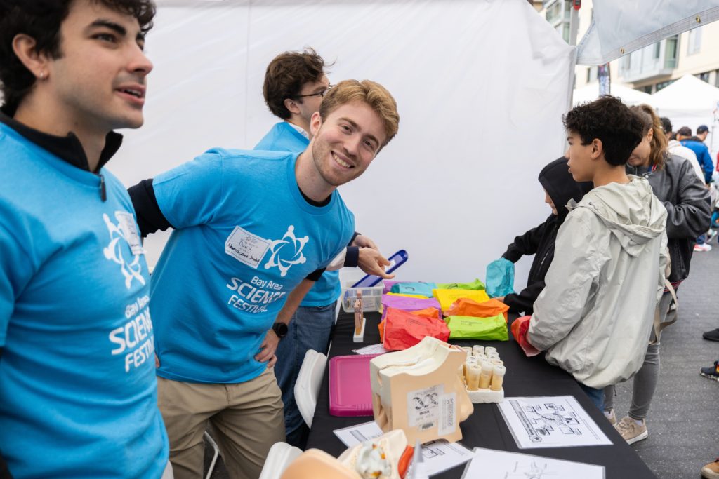 Festival volunteers dressed in turquoise t shirts interact with attendees