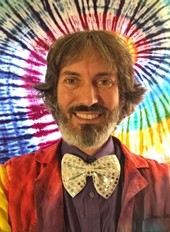 Headshot of Alan the Amazing, wearing a sequined bow tie, tie dyed lab coat, and tie dye background